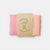 Pink fabric swatch with a brown label on a light gray background