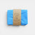 Blue fabric folded and tied with a brown paper strap on a white background