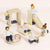 Wooden toy figures of children playing on a playground set with a slide, swing, and climbing structure.