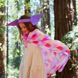 Child wearing a colorful scarf and purple headband in a forest setting