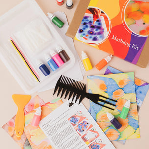 Marbling kit with bottles, brushes, and a comb on a light surface