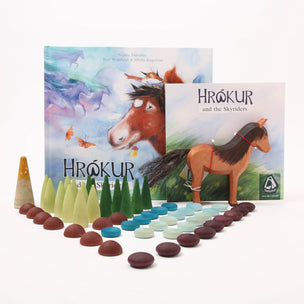 The 'Hrókur and the Skyriders' book, Ostheimer Pony and Grapat Set arranged on a white background, including the illustrated book, a wooden horse toy, and rows of coloured wooden pieces.