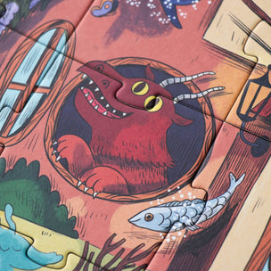 A close-up of a colorful illustrated jigsaw puzzle showing a red monster peeking out of a window, with other fantasy-themed pieces visible around it.