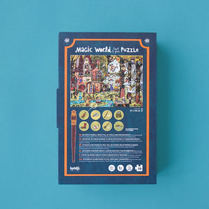 The packaging box of the 'Magic World Puzzle' by the brand 'hapyi' is shown against a solid teal-blue background. The box is dark blue with an orange border and features a colorful, highly detailed illustration of a magical shop scene on the front.
