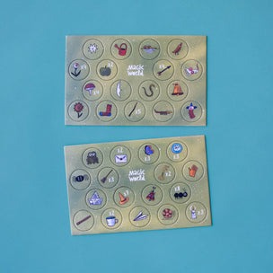 Two rectangular gold foil sticker sheets with circular cutouts containing various small illustrated icons, photographed on a solid turquoise-blue background.