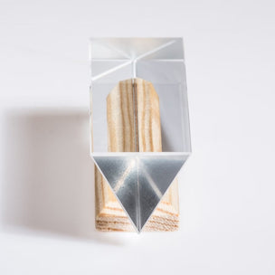 Geometric wooden block with triangular cutout inside a clear acrylic cube on a white background