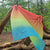 Colorful gradient towel hanging between two trees in a forest setting