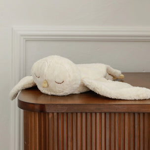 White plush toy resembling a dolphin on a wooden surface with a neutral wall background