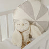Plush owl toy in a crib with geometric-patterned pillow
