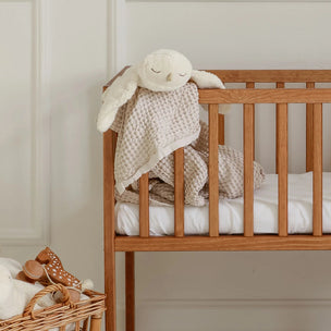 Wooden crib with baby blanket and toy in a nursery setting