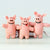 Three pink plush pig toys standing side by side on a light gray surface against a pale blue background. The tags read 'Schnauze' and 'Dachshund'.