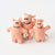 Three small pink felt pig toys with embroidered faces and small tags, standing together on a clean white background.