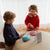 Two children playing with colorful toys on a light-colored surface.