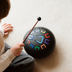 Child playing a colorful tabu drum pad on a light surface