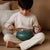 Child playing a small green instrument on a couch