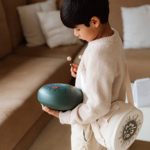 Child holding a green musical instrument in a living room setting