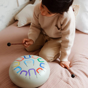 Child playing with a colorful drum on a couch