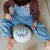Child playing with a colorful drum and drumsticks on a carpeted floor.