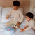 Two children playing with musical instruments on a bed.