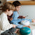 Two children playing with musical instruments on a light-colored floor.