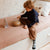 Child playing with a wooden drum on a bed in a cozy room.
