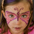 Child with butterfly face paint on a plain background