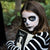 Person with skeleton makeup holding a book with a skeleton design outdoors