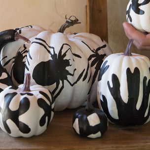 Decorative pumpkins with black and white designs on a wooden surface