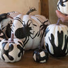 Decorative pumpkins with black and white designs on a wooden surface