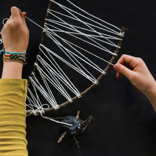 Person holding a string art project with a black background