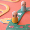 Wooden peg figures on a colorful board game with a smiley face design.