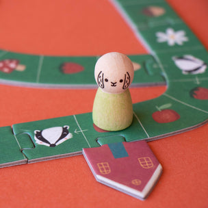 Board game piece on a colorful board with a house and cat illustration