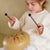 Child playing with a colorful percussion instrument against a plain background