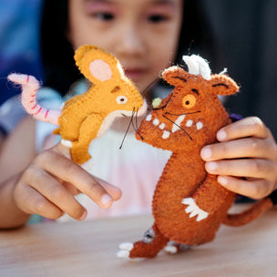 Child holding two felt animal toys on a wooden surface