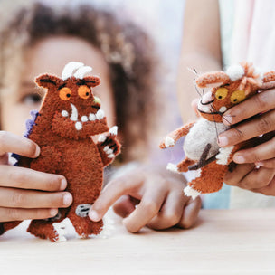 Two plush toys resembling characters from 'The Gruffalo' held by children.