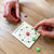 Game involving colored discs and a card with a diagram on a wooden table.