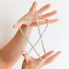 Hands playing with colorful string on a plain background