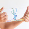 Hands holding a bow made of colorful yarn against a white background