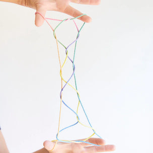 Colorful string art held between two hands on a white background