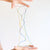Colorful string art held between two hands on a white background