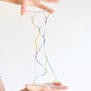 Colorful string art held between two hands on a white background