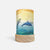 A cylindrical table lamp with a light wood base and a printed wrap featuring two dolphins swimming over blue water under a yellow sun, shown on a light gray background.