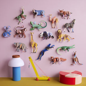 Colorful animal figurines on a pink wall with toys on a yellow surface