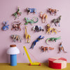 Colorful animal figurines on a pink wall with toys on a yellow surface