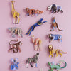 Collection of colorful animal figurines on a pink background