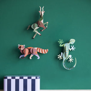 Decorative animal wall art on a green wall with a shelf below.