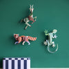 Decorative animal wall art on a green wall with a shelf below.