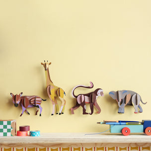 Wooden animal toys on a shelf against a yellow wall