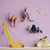 Studio Roof Colorful animal-shaped wall hooks on a pink wall with a yellow toy crane in the foreground.