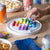 Colorful magnetic toy on a wooden table with snacks and drinks in the background